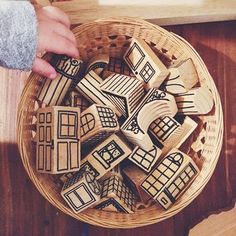 a basket filled with wooden cutouts sitting on top of a table next to a person's hand