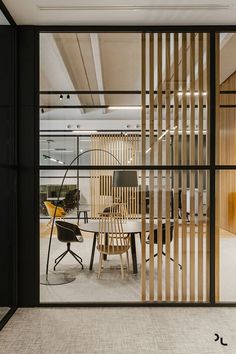 an office with glass walls and wooden slats on the wall, as well as a round table surrounded by chairs