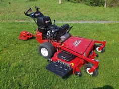 a red lawn mower sitting on top of a lush green field