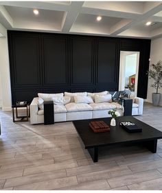 a living room filled with white furniture and black walls on either side of the couch