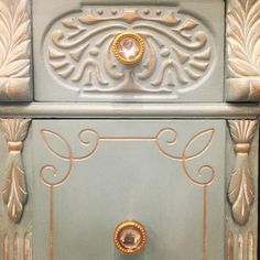 an ornately painted cabinet with gold trimmings and knobs on the doors