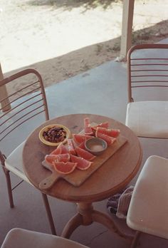 a wooden table topped with slices of grapefruit next to a bowl of fruit