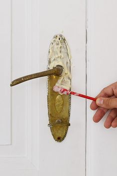 a hand holding a toothbrush in front of a door handle with ice cream on it