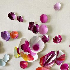 colorful paper flowers are scattered on a white surface