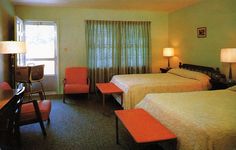 two beds in a hotel room with orange chairs and lamps on either side of them