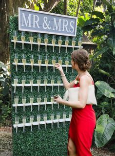 a woman in a red dress pointing at a sign with wine glasses on it that says mr and mrs