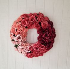 a wreath made out of pink roses on a white wall