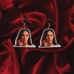 a pair of earrings with an image of a woman sticking her tongue out on it