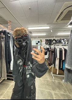 a person taking a selfie in a clothing store wearing a hoodie and jacket