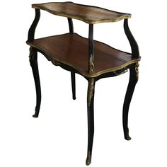 an ornate wooden table with two tiered shelves on one side and gold trimmings on the other