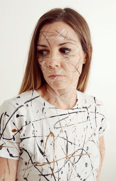 a woman with white paint on her face and black lines drawn across the top of her face