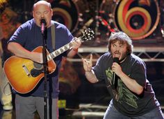 two men singing into microphones while holding guitars