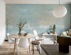 a dining room table with white chairs and a large painting on the wall behind it