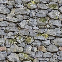 an old stone wall with moss growing on the sides and rocks all over it's surface