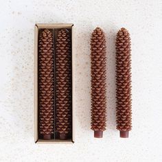 two pine cones are in a box on the table next to it is an empty one