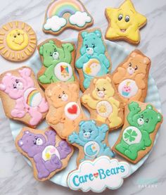 there are many decorated cookies on the plate with teddy bears and rainbows in the background