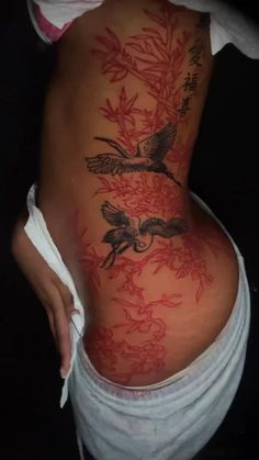 a woman's lower back tattoo with birds and flowers on the bottom part of her body