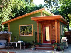 a small green house sitting in the middle of a yard with lots of trees around it