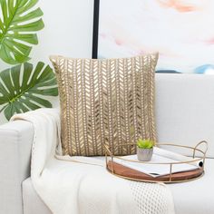 a white couch with a plant on it and a tray in front of the pillow