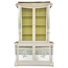 a white china cabinet with glass doors and drawers on the front, side by side