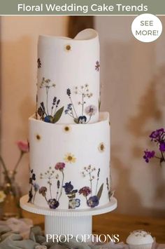 three tiered wedding cake with flowers painted on the side and text floral wedding cake trend see more