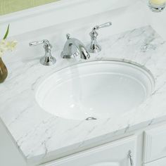 a bathroom sink with marble counter top and two faucets next to it,