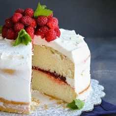 a cake with white frosting and raspberries is cut in half on a plate