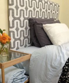 a bedroom with a bed, nightstand and flower vase on the table in front of it