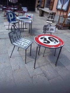 several chairs and tables are sitting on the side walk in front of a building with street signs