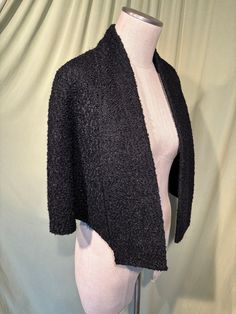 This is a lovely, vintage cape from the 1940s or so. No brand labels,. It is a lovely, black nubby boucle' fabric with a black satin lining. It is lightweight. It has a folded collar that extends into lapels all the way down the front, ending in small open pockets. It is longer in front than in back. Measures 15" across the shoulders, 20.5" from shoulder to hem in front & 19" from neckline to hemline in back.  Condition is very good. No bare patches or bald areas. No soil or stains, no wear. Ver Chic Black Capelet, Vintage Winter Capelet, Vintage Cape-style Costume Outerwear, Black Vintage Outerwear With Button Closure, Vintage Wool Cape Outerwear, Fit And Flare Coat, Wool Cape Coat, Trim Scarf, Cape Shawl