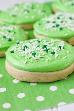 green cookies with white sprinkles are sitting on a polka dot tablecloth