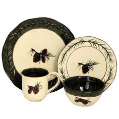 a black and white dinnerware set with pine cones on the rim, two cups and one saucer