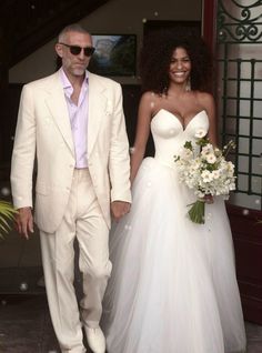 the bride and groom are holding hands as they walk down the steps together in their wedding dresses