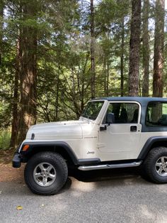 a white jeep is parked in the woods