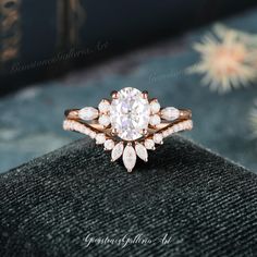 a close up of a diamond ring on top of a black velvet surface with flowers in the background