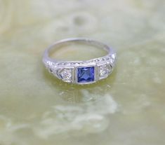 Vintage 18K White Gold Art Deco Sapphire and Diamond Ring, 4mm square central fine blue sapphire, round diamond, side stones, pierced filigree top, Ring size 6, Circa 1930, weight 2.14 grams Stock # BB140R08 This listing contains photographs of the actual item you will receive. Our items are in excellent condition with little or no signs of wear and many are one of a kind pre-owned estate finds. Please look closely at the pictures in this listing as they are part of the product description. Plea Formal Sapphire Jewelry With Single Cut Diamonds, Art Deco Sapphire Jewelry With Center Stone, Hallmarked Heirloom Sapphire Jewelry, Heirloom Sapphire Jewelry In Platinum, Heirloom Sapphire Platinum Jewelry, Antique Blue Diamond Jewelry, Antique Sapphire Jewelry With Single Cut Diamonds, Art Deco Blue Jewelry With Single Cut Diamonds, Vintage Sapphire Jewelry For Anniversary