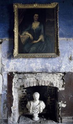 an old fireplace with a busturine in front of it and a painting on the wall