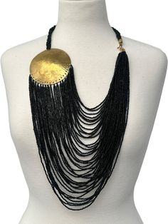 Add a touch of African elegance to your jewellery collection with this authentic long black beaded brass necklace. The necklace features a beautiful pendant made of brass, adorned with intricate beadwork in a classic African style. The black colour of the beads adds a touch of sophistication to the piece, making it perfect for any occasion. Crafted with high-quality materials, this necklace is a must-have for any jewellery enthusiast. The pendant hangs delicately from an elegant chain, making it a perfect accessory for any outfit. Whether you're looking to add a touch of African culture to your wardrobe or simply want to make a statement, this necklace is the perfect choice. Colour - Black Length - 22inches Material: Beads, Brass African Elegance, Style Africain, Chain Making, African Style, Disc Pendant, African Beads, Brass Necklace, Wooden Earrings, Body Jewellery