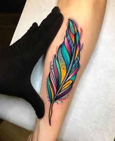 a colorful feather tattoo on the leg