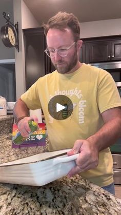 a man in glasses is making something on top of a counter with an open box