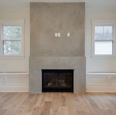 an empty room with a fireplace and two windows