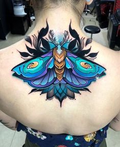 the back of a woman's neck with a colorful butterfly tattoo on it