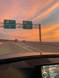 the sun is setting on an interstate highway with traffic signs in front of it and cars driving down the road