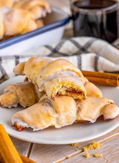 a white plate topped with pastries on top of a wooden table next to cinnamon sticks