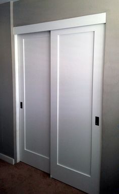 two white doors in a room with carpeting