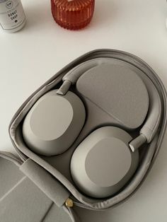 two headphones are sitting in a case on a table next to an orange vase