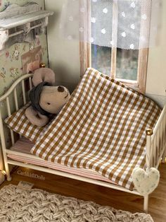 a teddy bear laying in a crib next to a window with curtains and lights