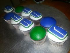 cupcakes with green and blue frosting sitting on top of a metal tray