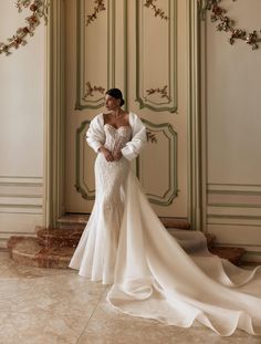 a woman in a wedding dress standing next to a wall