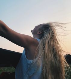 a woman with long hair standing in the back of a car looking up into the sky